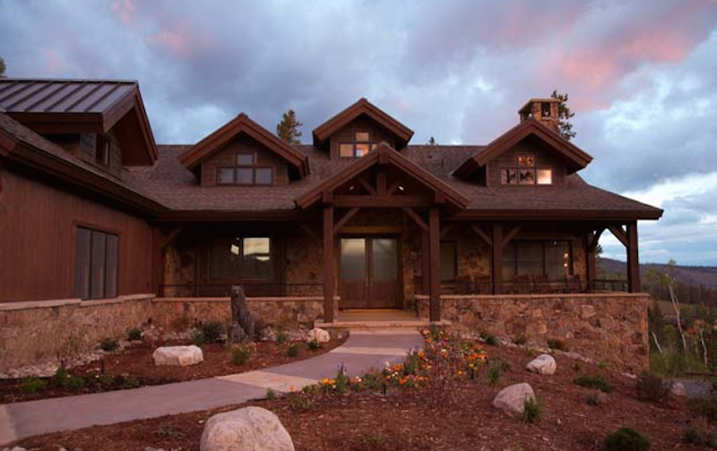 На фото: двухэтажный, коричневый дом среднего размера в стиле рустика с облицовкой из камня и полувальмовой крышей