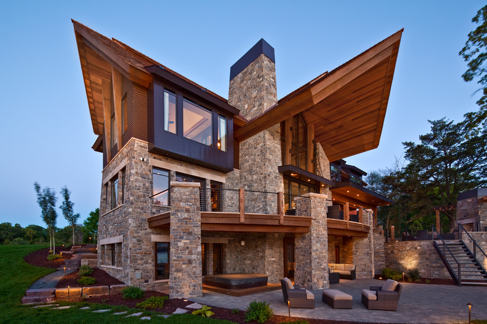 На фото: огромный, трехэтажный, коричневый дом в современном стиле с облицовкой из камня