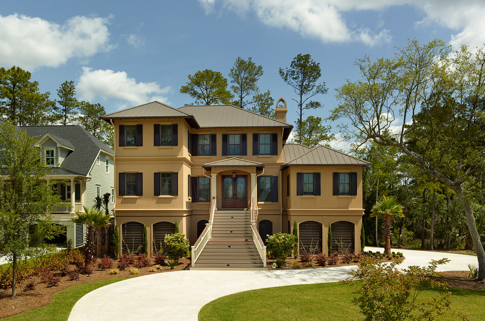 Traditional beige three-story stucco exterior home idea in Charleston with a hip roof