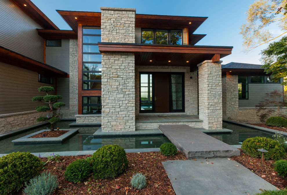Modelo de fachada de casa beige contemporánea de tamaño medio de dos plantas con revestimientos combinados, tejado a cuatro aguas y tejado de teja de madera