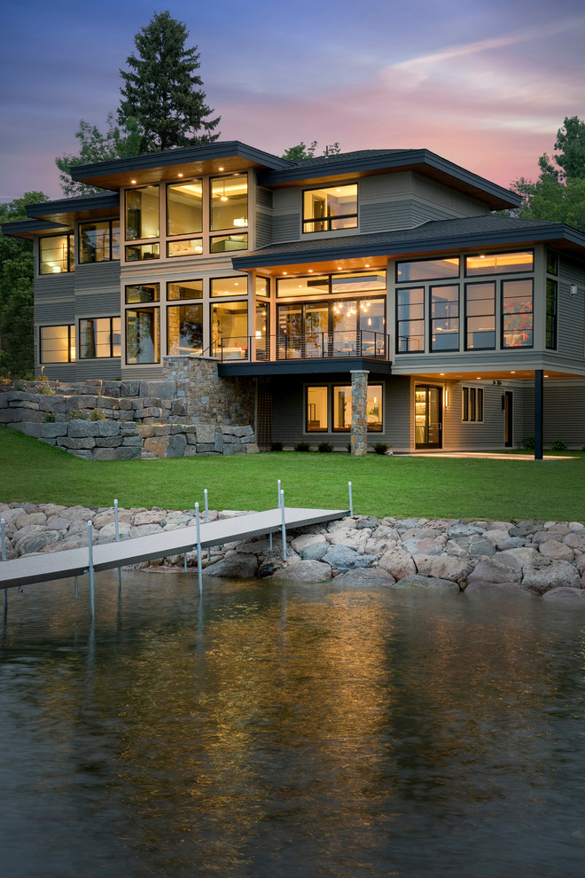 Стильный дизайн: огромный, трехэтажный, серый дом в современном стиле с облицовкой из камня и вальмовой крышей - последний тренд