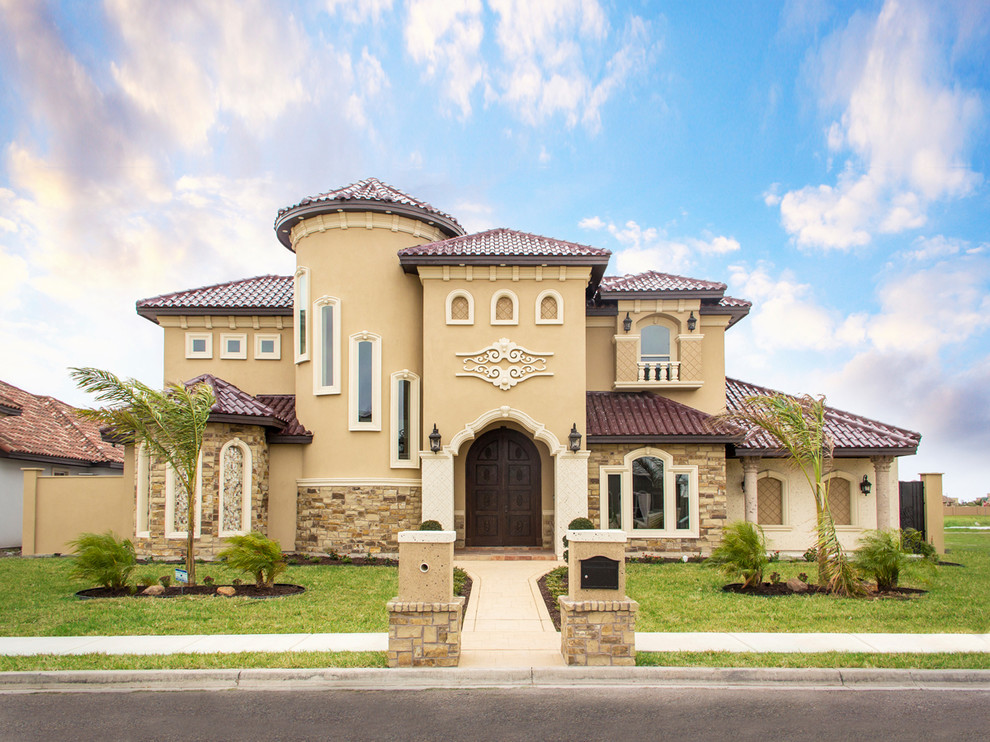 Large tuscan beige two-story stucco house exterior photo in Austin with a gambrel roof and a shingle roof