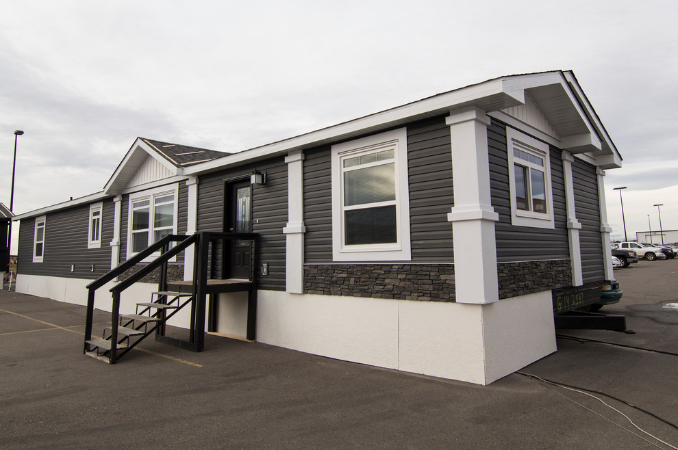 Cette image montre une façade de maison grise chalet de taille moyenne et de plain-pied avec un revêtement en vinyle.