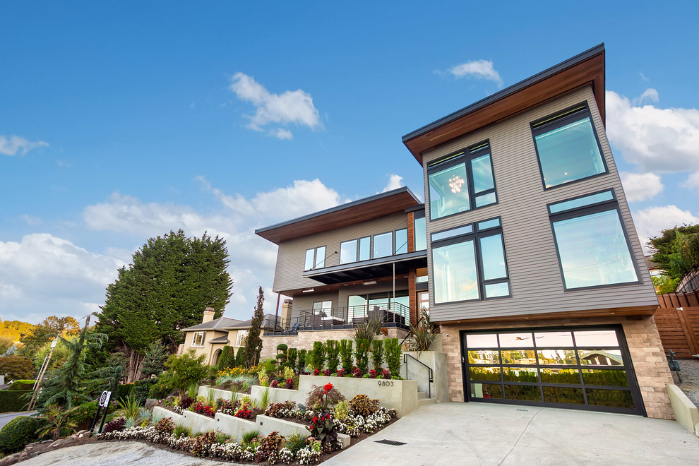 Geräumiges, Dreistöckiges Modernes Einfamilienhaus mit Mix-Fassade, grauer Fassadenfarbe, Flachdach und Blechdach in Seattle