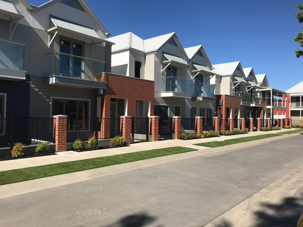 This is an example of a beige modern two floor brick detached house in Other with a pitched roof and a metal roof.