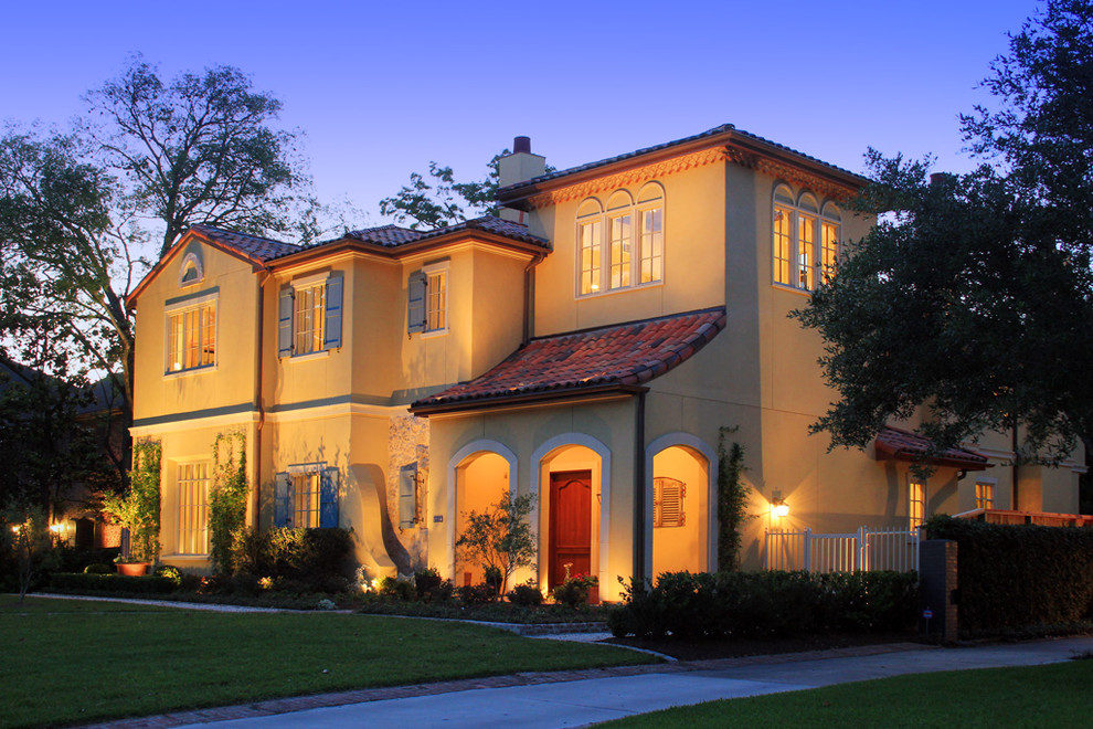 Example of a large tuscan yellow two-story stucco exterior home design in Houston