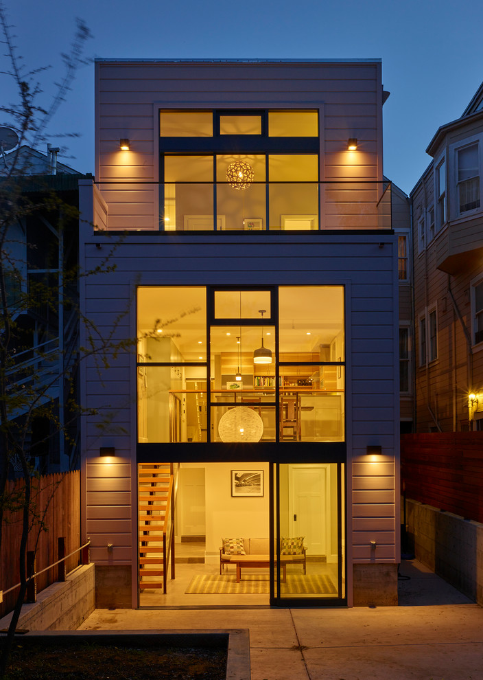 Cette photo montre une grande façade de maison beige tendance en bois à deux étages et plus avec un toit plat.