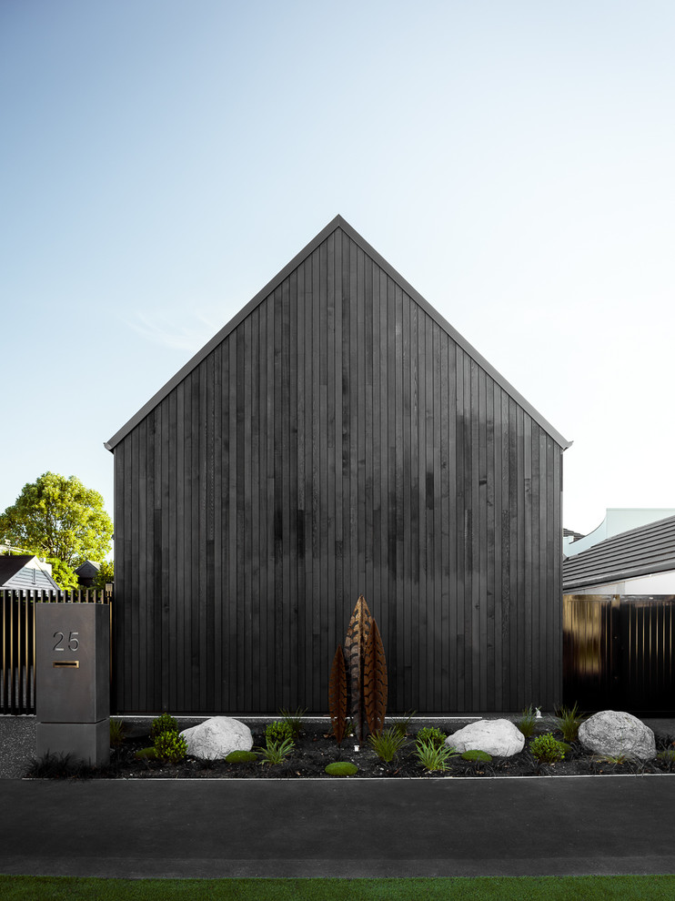 Large mountain style black two-story wood exterior home photo in Christchurch with a metal roof
