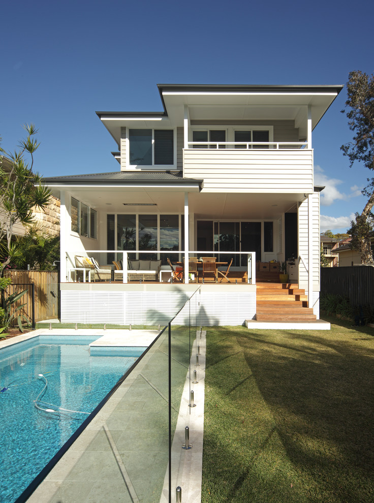 Inspiration pour une façade de maison grise marine en panneau de béton fibré à un étage avec un toit à quatre pans.