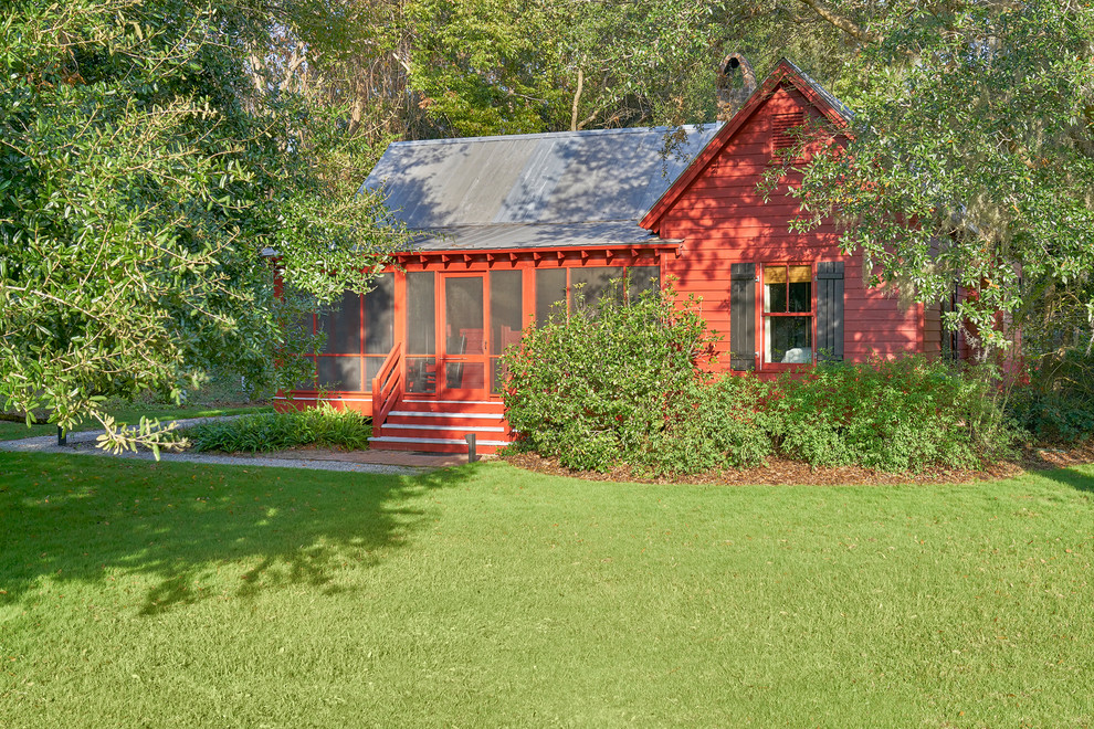 Esempio della villa rossa classica a un piano di medie dimensioni con rivestimento in legno, tetto a capanna e copertura in metallo o lamiera