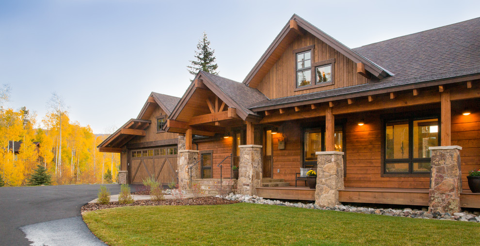 Ejemplo de fachada de casa marrón rural grande de dos plantas con revestimientos combinados, tejado a dos aguas y tejado de teja de madera