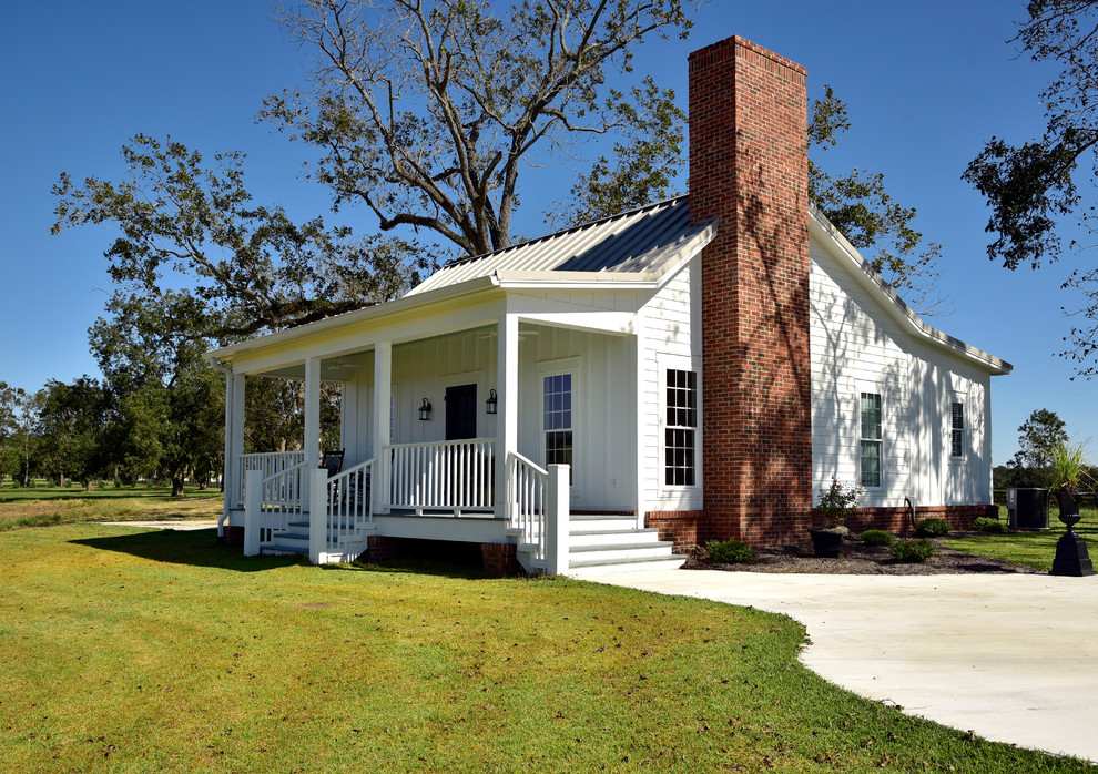 Kleines, Einstöckiges Landhaus Einfamilienhaus mit Faserzement-Fassade, weißer Fassadenfarbe, Satteldach und Blechdach