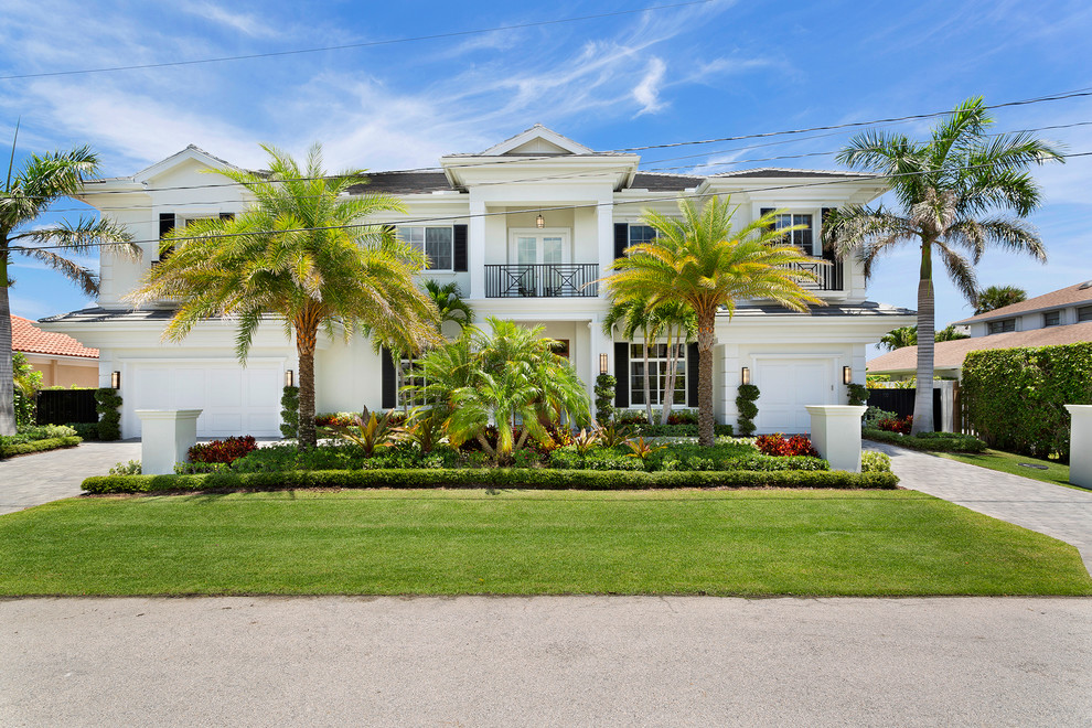 Imagen de fachada de casa blanca tropical extra grande de dos plantas con revestimientos combinados, tejado a dos aguas y tejado de varios materiales