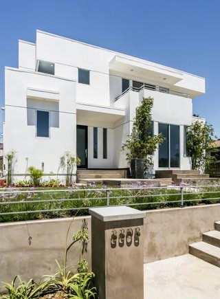 Réalisation d'une façade de maison blanche minimaliste en béton de taille moyenne et à un étage avec un toit plat.