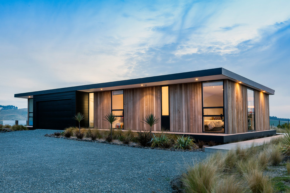 На фото: одноэтажный, деревянный, коричневый частный загородный дом среднего размера в современном стиле с плоской крышей и металлической крышей с