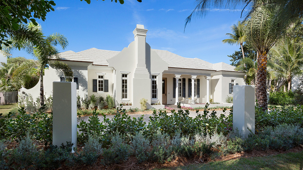 Example of a mid-sized island style white one-story concrete house exterior design in Miami with a hip roof and a tile roof