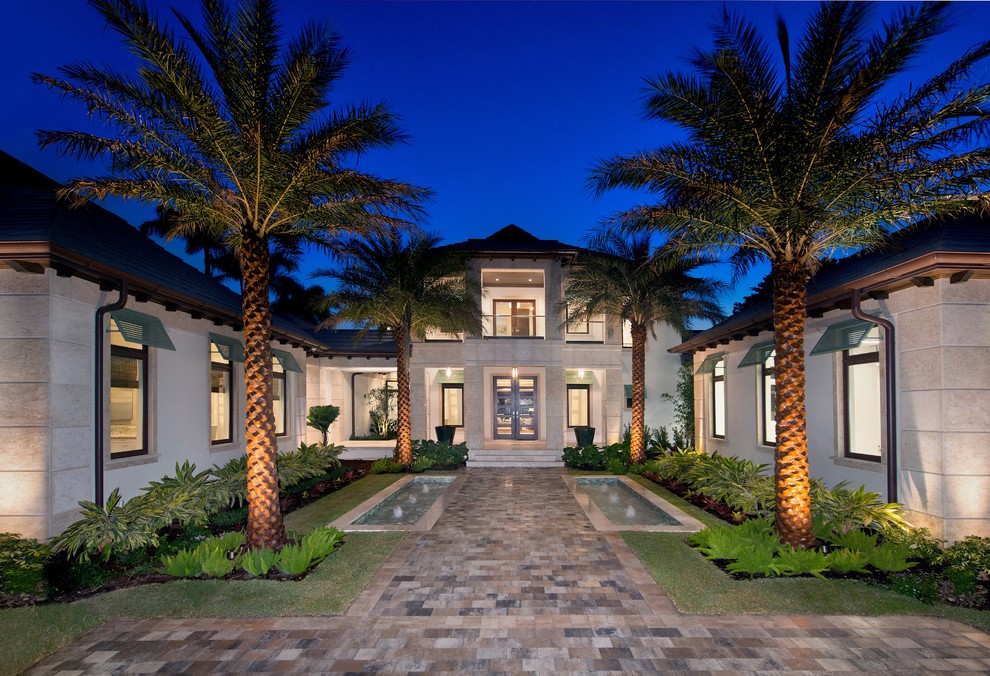 Inspiration for a coastal beige two-story stone house exterior remodel in Miami with a tile roof