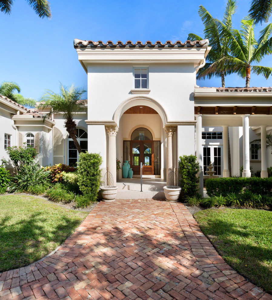 Mid-sized mediterranean beige one-story concrete house exterior idea in Miami with a hip roof and a shingle roof