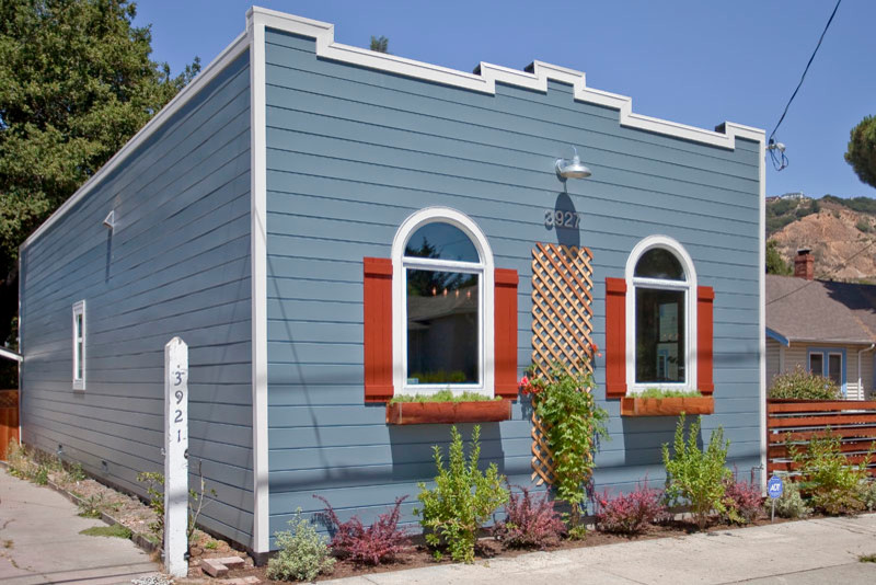 Diseño de fachada de casa azul bohemia pequeña de una planta con revestimiento de madera y tejado plano