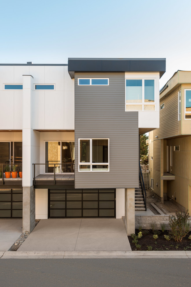 Ejemplo de fachada de casa pareada gris moderna de tamaño medio de tres plantas con revestimientos combinados, tejado plano y tejado de metal