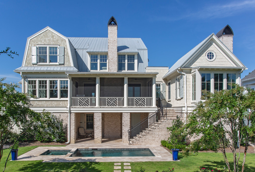 Dreistöckiges Maritimes Haus mit beiger Fassadenfarbe, Mansardendach und Blechdach in Charleston