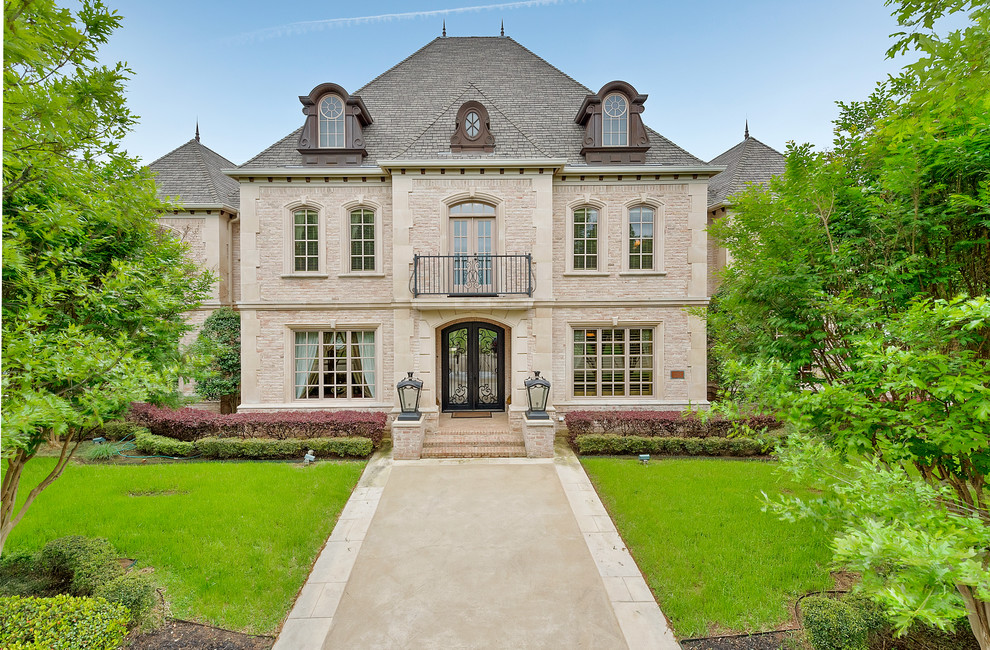 This is an example of a traditional brick house exterior in Dallas with three floors and a hip roof.