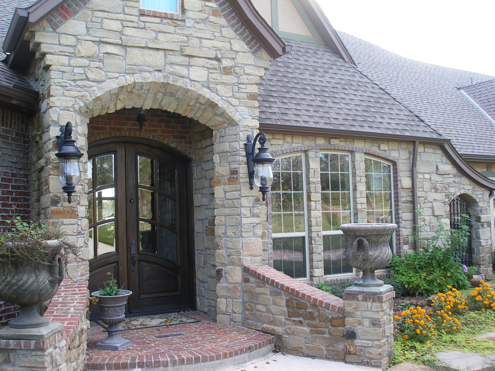 Photo of a large and beige mediterranean two floor house exterior in Oklahoma City with stone cladding and a hip roof.