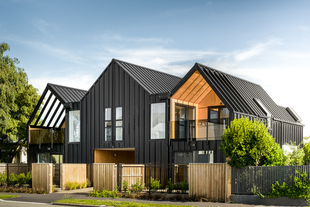Small and black modern two floor flat in Christchurch with metal cladding, a pitched roof and a metal roof.