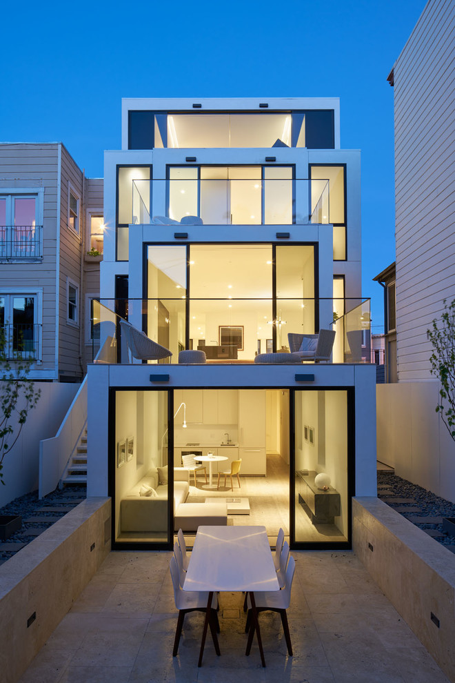 Immagine della facciata di una casa bianca contemporanea a tre piani con rivestimento in vetro