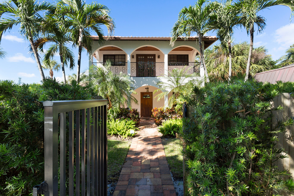 Esempio della villa beige tropicale a due piani con rivestimenti misti, tetto a padiglione e copertura a scandole