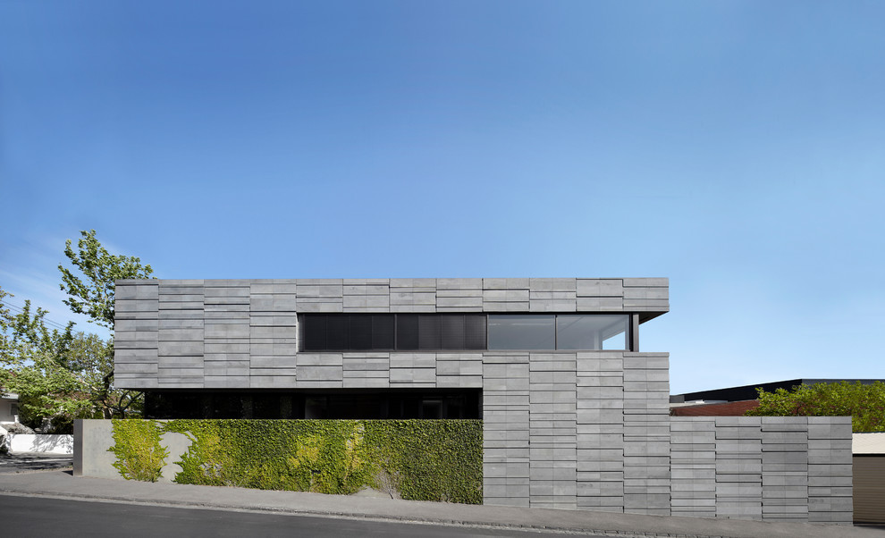 Modelo de fachada gris actual grande de dos plantas con revestimiento de piedra y tejado plano