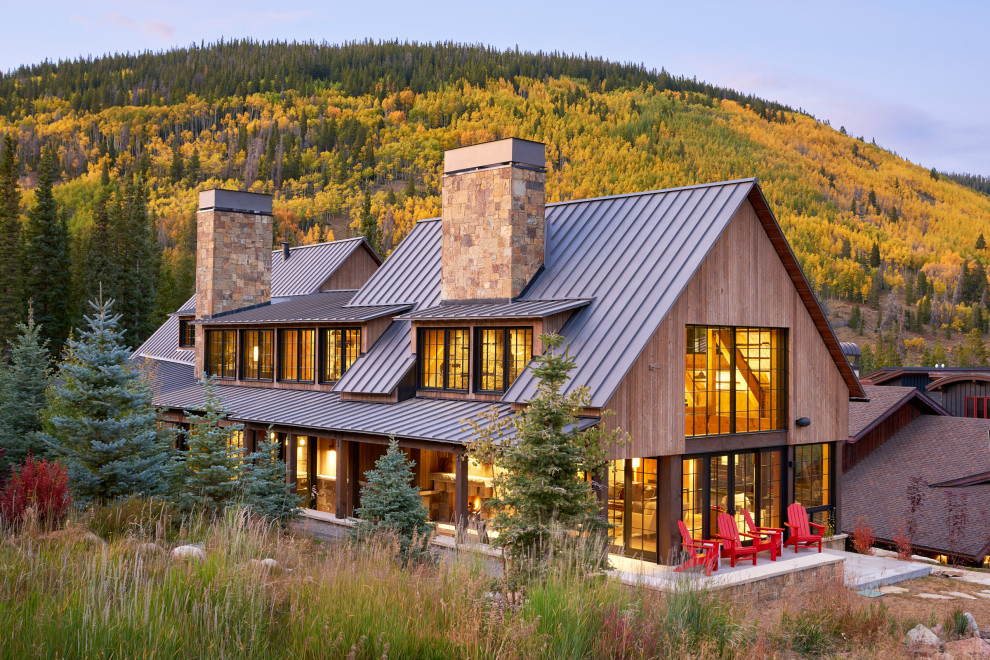 Cette image montre une façade de maison marron chalet en bois à un étage avec un toit à deux pans et un toit en métal.