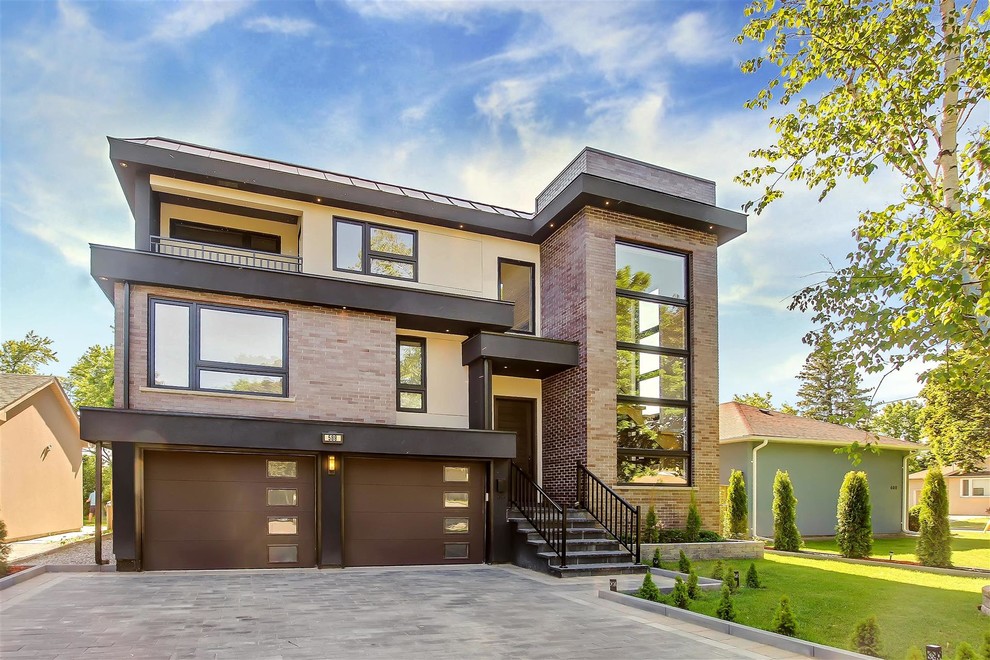 This is an example of a medium sized and brown modern split-level brick house exterior in Toronto with a flat roof.