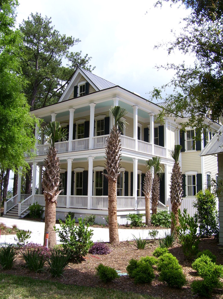 Inspiration för ett tropiskt beige hus, med två våningar