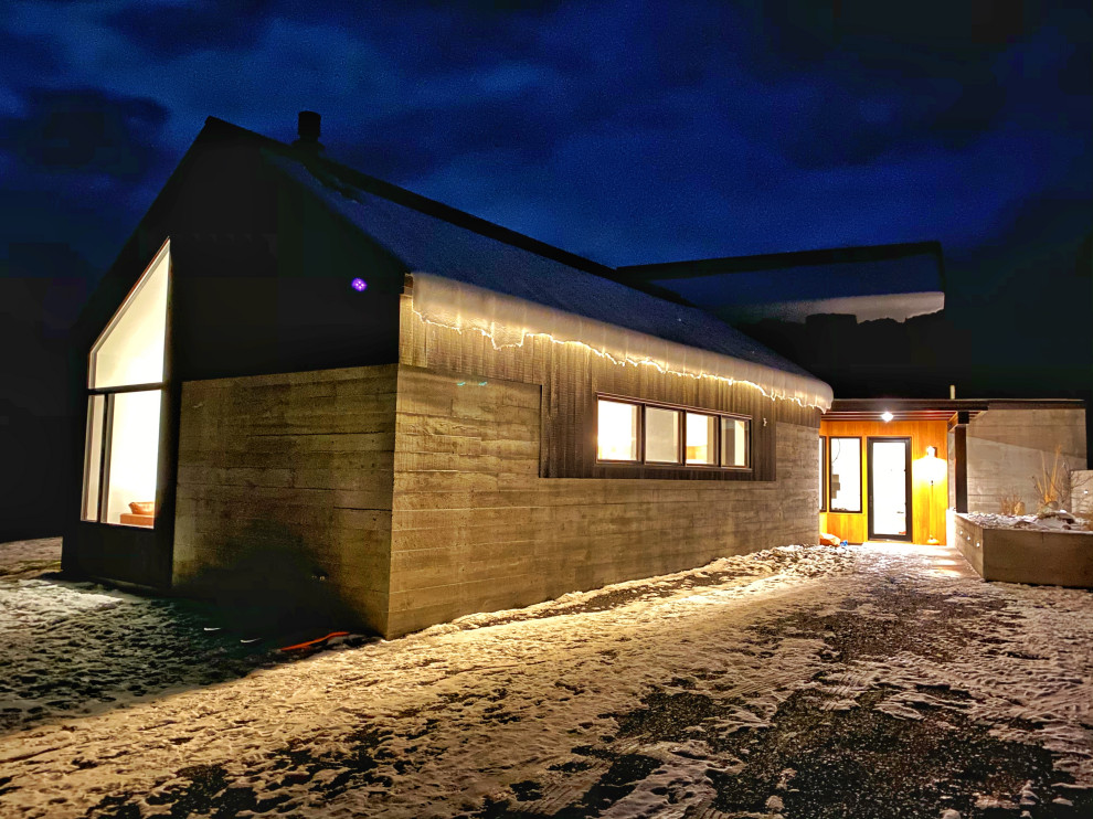 Esempio della villa nera scandinava di medie dimensioni con rivestimento in cemento, tetto a capanna e copertura in metallo o lamiera
