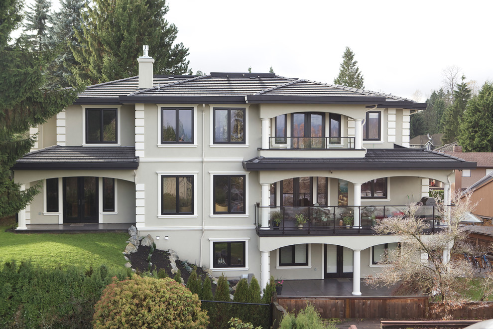 Diseño de fachada beige clásica grande de tres plantas con revestimiento de estuco y tejado a cuatro aguas