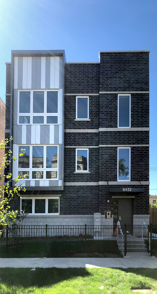 Immagine della facciata di un appartamento nero moderno a tre piani con rivestimento in mattoni e tetto piano