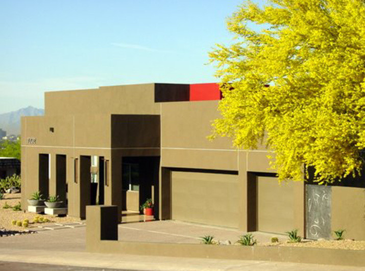 На фото: одноэтажный, коричневый дом среднего размера в стиле ретро с облицовкой из самана и плоской крышей с