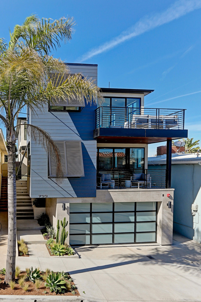 Cette image montre une grande façade de maison bleue design à deux étages et plus avec un revêtement mixte et un toit plat.