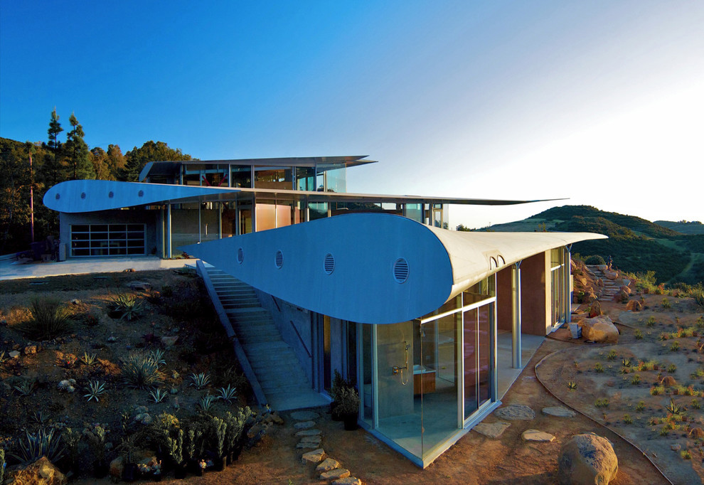 Trendy three-story glass exterior home photo in Los Angeles