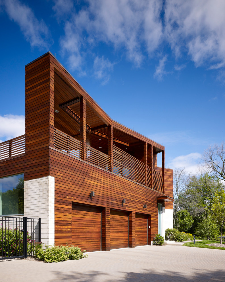 Cette image montre une très grande façade de maison multicolore design en bois à un étage avec un toit plat.