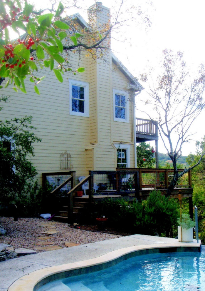 Foto della villa piccola gialla country a due piani con rivestimento con lastre in cemento, tetto a capanna e copertura a scandole