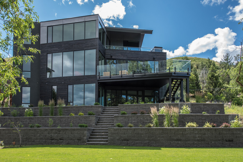 This is an example of a black contemporary house exterior in Vancouver with three floors and a flat roof.