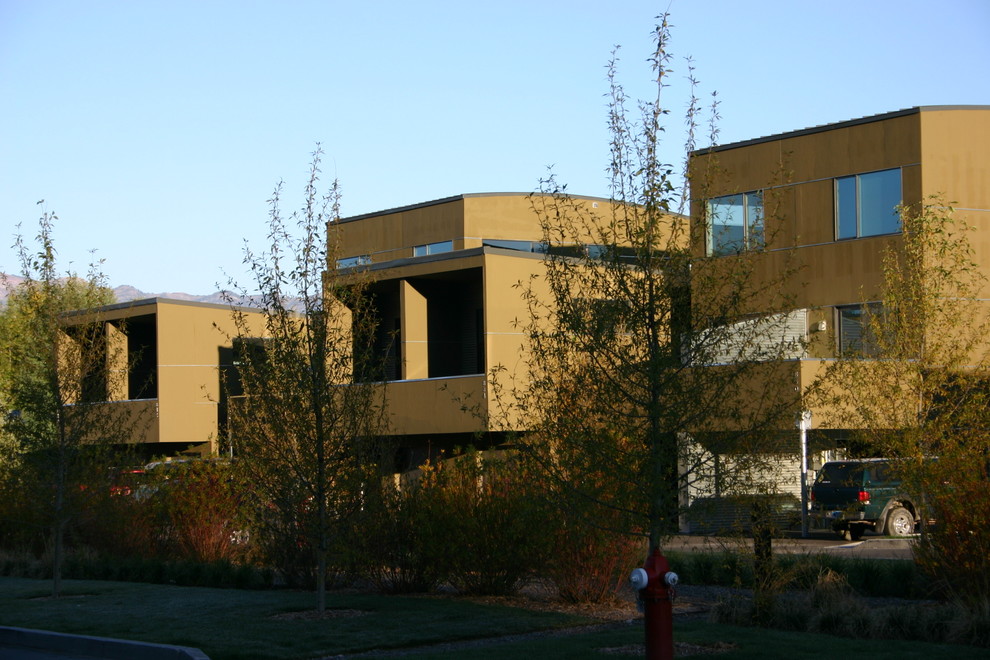 Foto della facciata di una casa a schiera ampia grigia contemporanea a tre piani con rivestimenti misti, tetto piano e copertura in metallo o lamiera