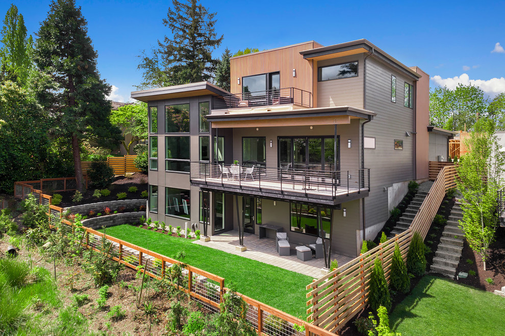На фото: трехэтажный, серый частный загородный дом в современном стиле с комбинированной облицовкой