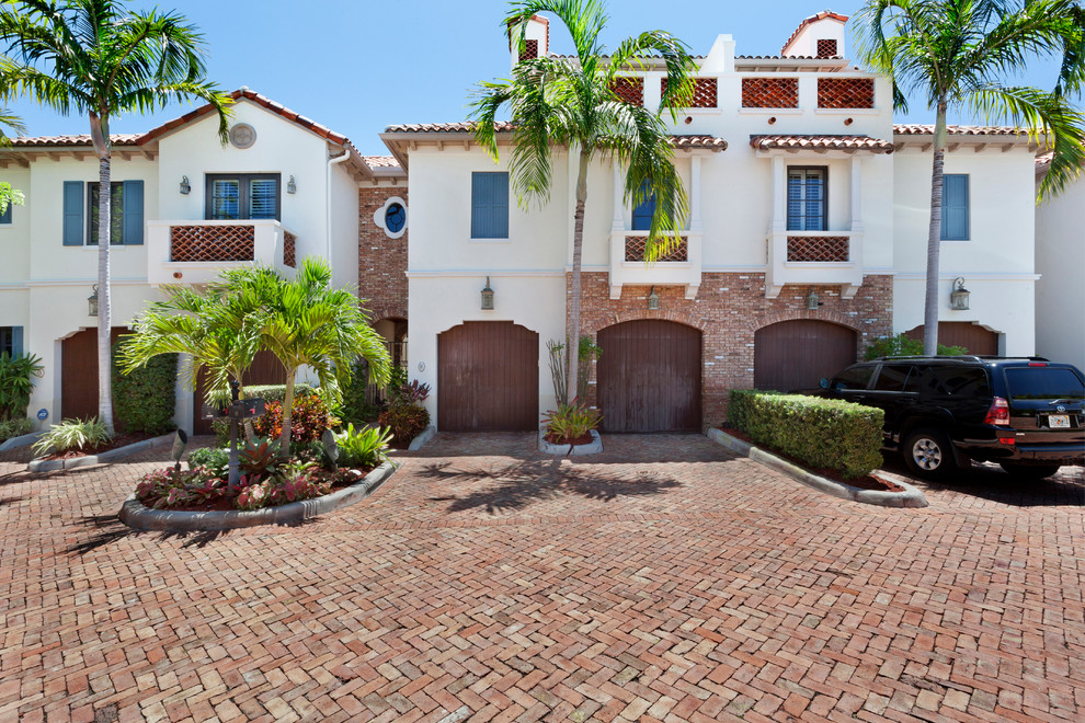 Large and white world-inspired brick terraced house in Miami with three floors, a hip roof and a tiled roof.