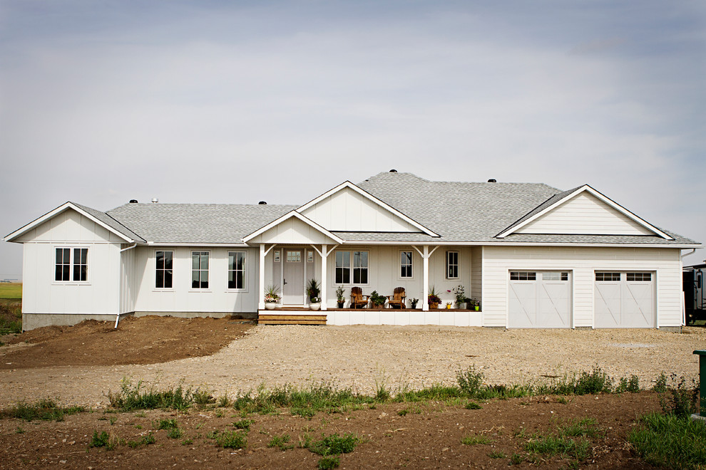 На фото: одноэтажный, белый частный загородный дом в стиле кантри с комбинированной облицовкой, полувальмовой крышей и крышей из гибкой черепицы с