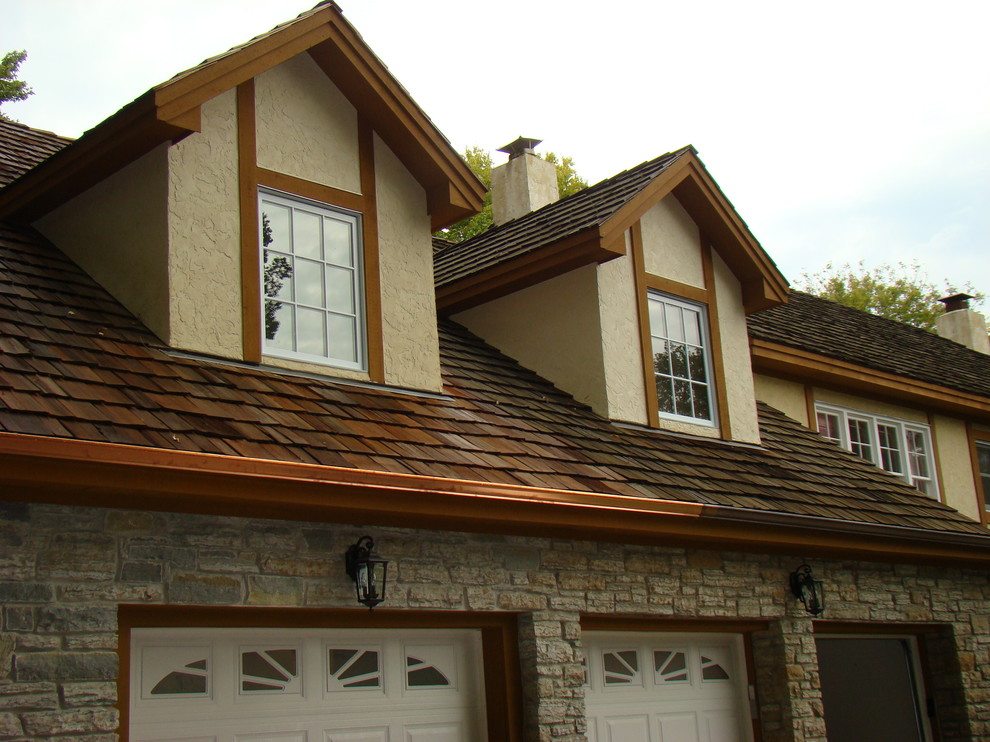 Esempio della facciata di una casa grande beige eclettica a due piani con rivestimento in pietra e tetto a capanna