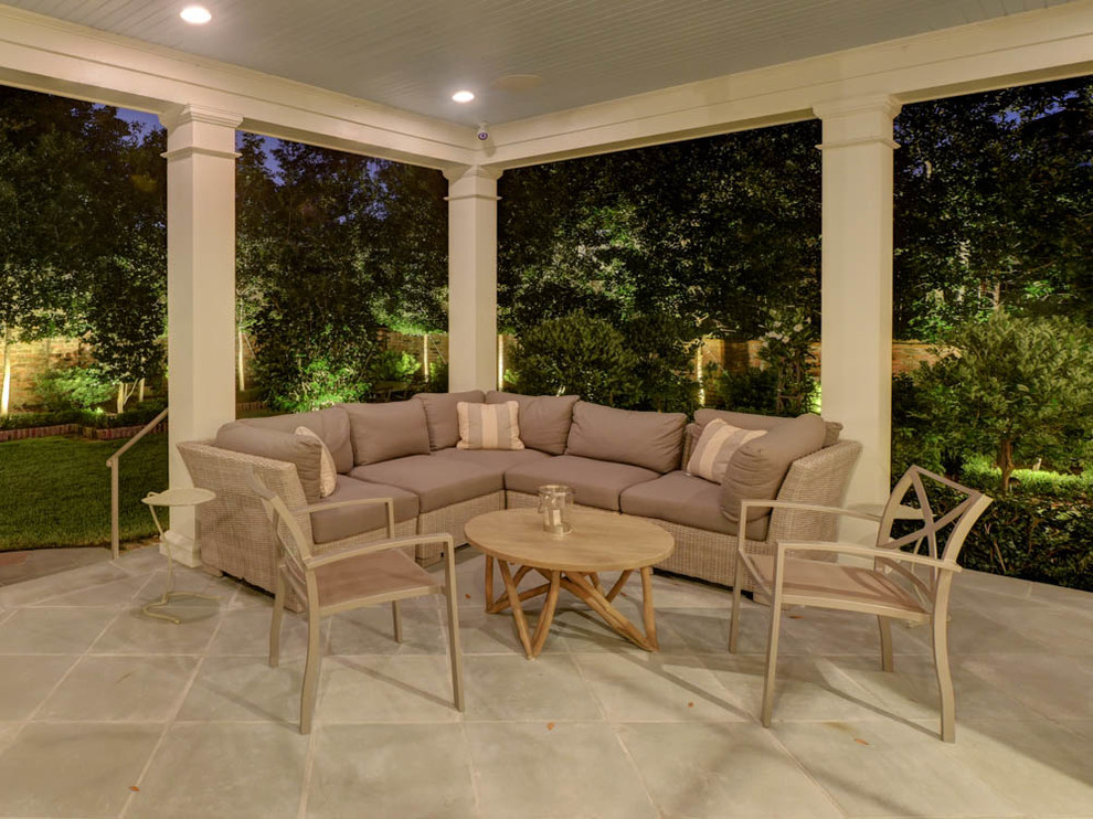 Large traditional back patio in New Orleans with natural stone paving and a roof extension.