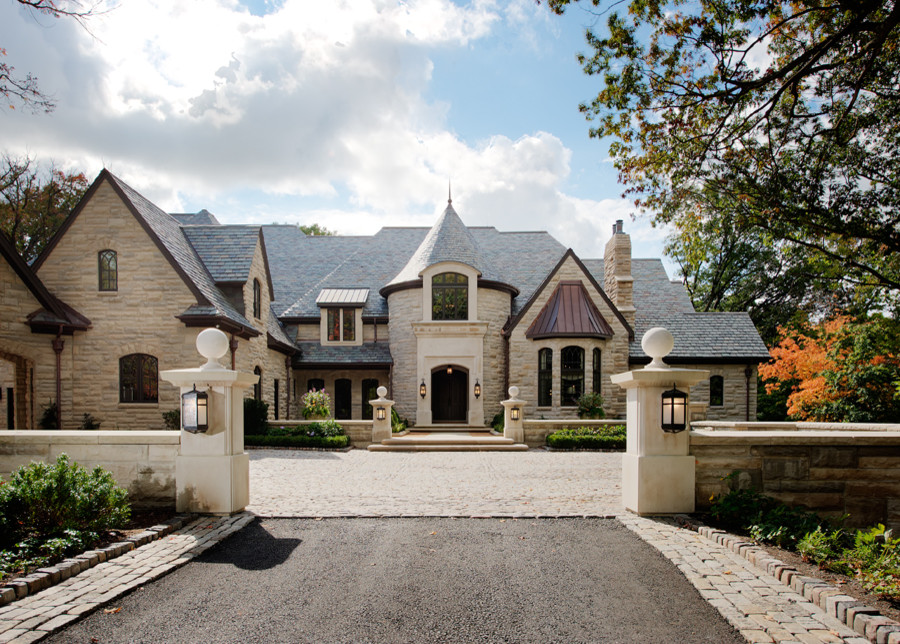 На фото: огромный, бежевый частный загородный дом в классическом стиле с облицовкой из камня и черепичной крышей